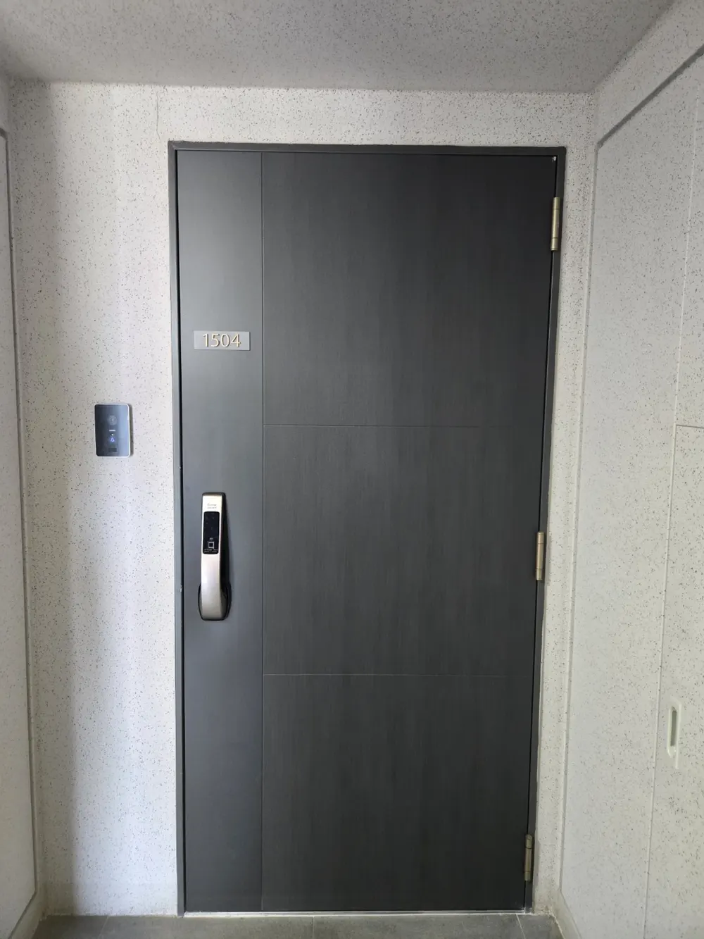현관문 측면 경첩 부위가 노출된 시공 현장 사진