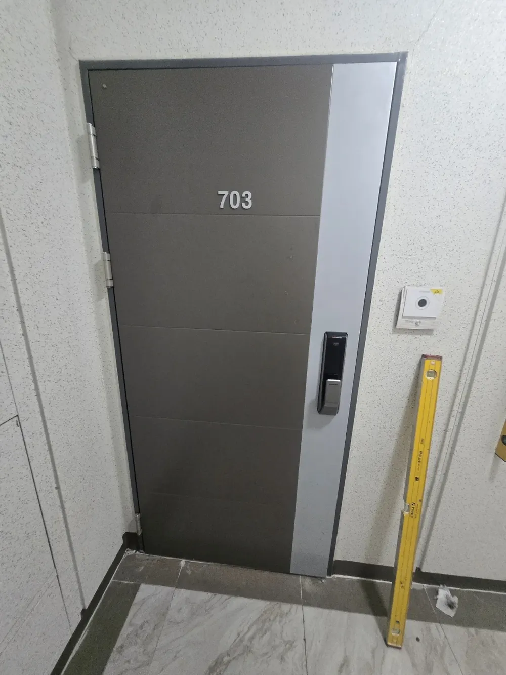 현관문 하단 경첩 세 개가 노출된 시공 현장 사진